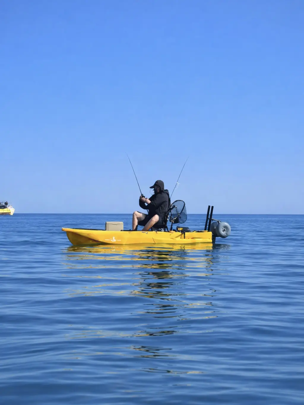 A man fishing from a kayak on ocean waters under a clear blue sky, showcasing coastal kayak fishing and outdoor recreation in Canada and the United States